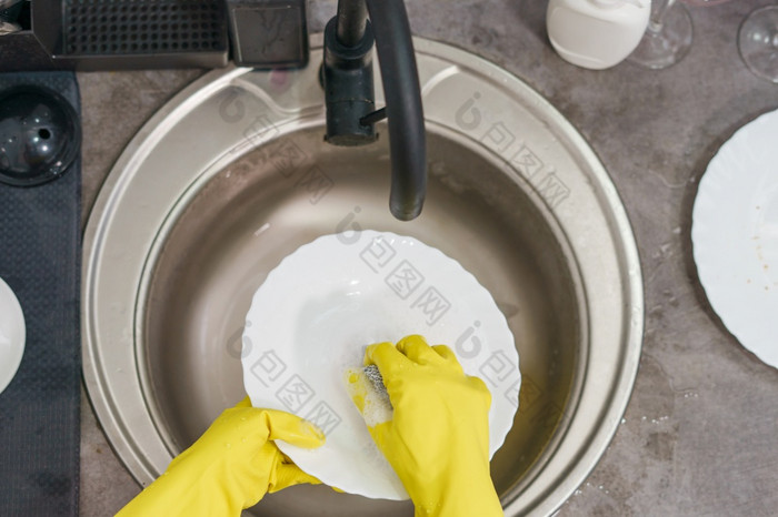 关闭黄色的橡胶保护手套女未知的女人女人rsquo手手动洗盘子菜的厨房的水槽一边视图首页的利用水一天前视图