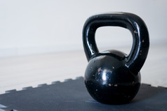 关闭黑色的铁金属壶铃格里亚重量培训设备的锻炼席的地板上首页一天