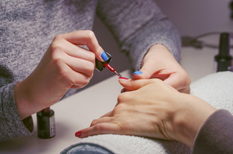 关闭手未知的高加索人女女人女孩持有指甲波兰的刷朋友手指指甲修指甲沙龙<strong>首页</strong>与红色的过来这里美容师<strong>手绘</strong>画客户端美概念