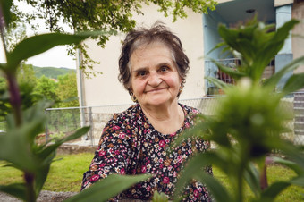 肖像高级养老金领取者高加索人女人女农民<strong>站前</strong>面的房子她的首页村的农村看的相机微笑之间的绿色植物快乐真正的人