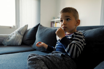 肖像一个小三个年老高加索人男孩小孩子孩子坐着的沙发床上首页持有湿擦餐巾手擦拭口脸清洁和消毒后吃一边视图