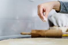 关闭手未知的女人持有面粉和传播在准备面团的厨房计数器使自制的粘贴羊角面包首页