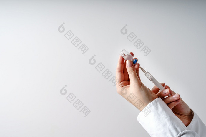 关闭手未知的高加索人女人医生持有注射器与针和疫苗注射前面白色墙新冠病毒疫苗接种概念医疗保健和医学复制空间
