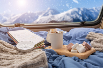 杯热咖啡与棉花糖附近的窗口俯瞰的雪山山的商队野营车的冬天季节旅行野营概念