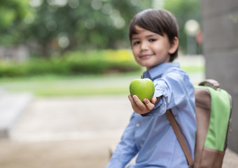 可爱的小男孩穿<strong>蓝色</strong>的衬衫和携带学生背包显示苹果为早餐之前学校早餐重要的为孩子发展<strong>健康</strong>和<strong>健康</strong>