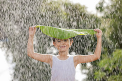 男孩微笑有有趣的站与叶她的头站的雨