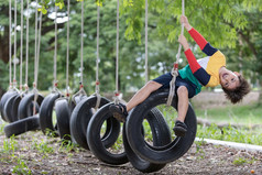 男孩穿明亮的彩色的衣服玩轮胎摇摆不定的挂操场上和有有趣的健康的夏天假期活动