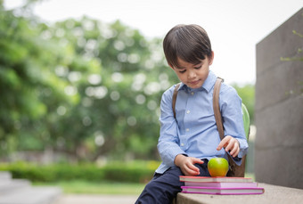 可爱的小男孩穿蓝色的衬衫和携带学生背包收到苹果从妈妈。为<strong>早餐</strong>之前学校<strong>早餐</strong>重要的为孩子发展<strong>健康</strong>和<strong>健康</strong>