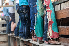 行牛仔竞技表演牛仔站老木铁路与蓝色的牛仔裤靴子和家伙
