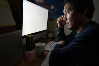 肖像亚洲商人坐着和工作硬的表格与前面电脑桌面工作的地方晚些时候与严重的行动工作硬和太晚些时候概念