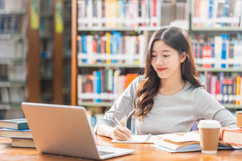 亚洲年轻的学生休闲西装做家庭作业和使用技术移动PC图书馆<strong>大学通知书</strong>的与各种各样的书和静止的在的书架子上背景回来学校