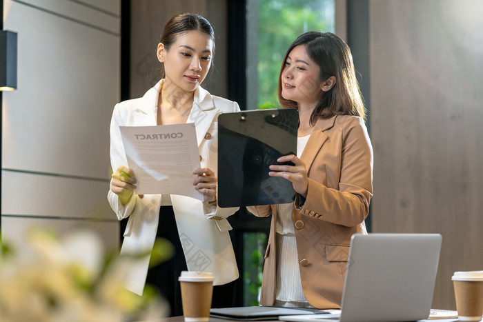 两个亚洲女商人讨论与的合作伙伴业务关于业务合同技术移动PC现代会议房间办公室工作空间咖啡打破合作伙伴和的同事概念