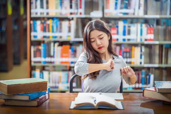 亚洲年轻的学生休闲西装阅读和做拉伸自己图书馆<strong>大学通知</strong>书的与各种各样的书和静止的的木表格在的书架子上回来学校