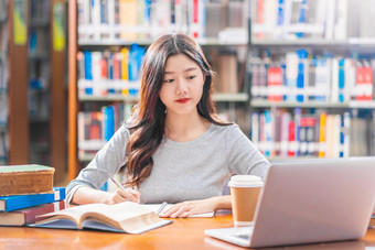 亚洲年轻的学生休闲西装做家庭作业和使用技术移动PC图书馆大学通知书的与各种各样的书和静止的在的书架子上背景回来学校