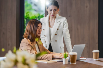 两个亚洲女商人工作与的合作伙伴业务通过技术移动PC现代会议房间办公室工作空间咖啡打破合作伙伴和的同事概念
