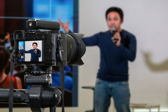 专业数字mirrorless相机与麦克风的三脚架记录视频博客亚洲演讲者的阶段研讨会相机为摄影师视频和技术生活流媒体概念