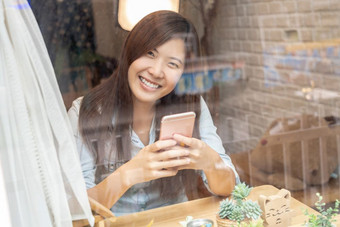 亚洲女商人手使用的聪明的移动电话与幸福行动的桌子上旁边的玻璃工作场所联合办公空间现代办公室业务生活方式概念