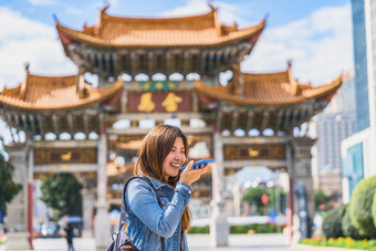 亚洲旅行者女人使用聪明的移动电话为的声音命令录音机翻译当旅行在的jinbi广场<strong>昆明</strong>中国旅行和旅游著名的的地方和具有里程碑意义的概念