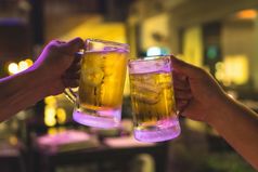 两个眼镜啤酒干杯在一起之间的朋友的低光酒吧和餐厅放松和喝概念