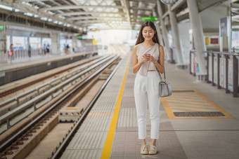 年轻的亚洲女人乘客使用社会网络通过聪明的移动电话地铁火车当旅行大城市日本中国人朝鲜文生活方式和每天生活通勤和运输概念