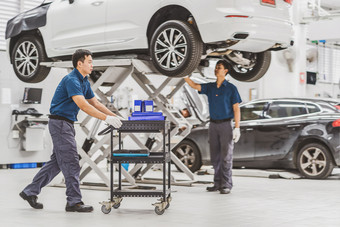 亚洲机械师推车与车设备在的同事检查和修复的车维护服务中心哪一个部分展厅技术员工程师专业工作
