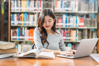 亚洲年轻的学生休闲西装做家庭作业和使用技术移动PC图书馆大学通知书的与各种各样的书和静止的在的书架子上背景回来学校