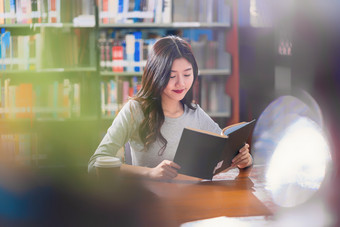 亚洲年轻的学生休闲西装阅读的书与杯咖啡图书馆大学通知书的的木表格在的书架子上背景回来学校概念