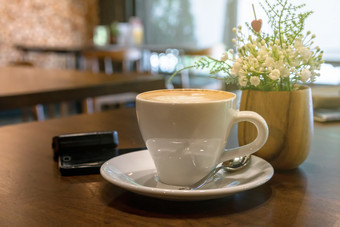 咖啡杯的表格与假的装修假的花和移动电话咖啡馆商店喝概念