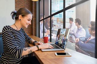 赶时髦的人年轻的女人自由职业者使用的技术移动PC有视频会议通过监控显示为工作的阁楼咖啡馆工作场所有创意的启动和企业家业务概念