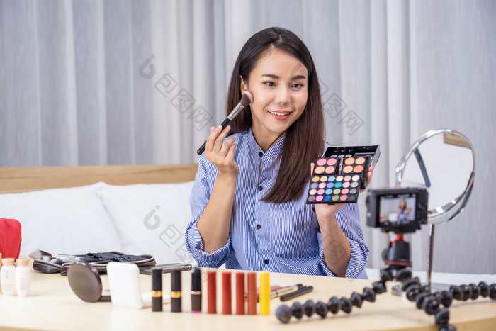 魅力亚洲女人美博主视频博客显示使与调色板和生活社会网络媒体通过视频移动电话视频记录自己化妆教程化妆品视频博客概念