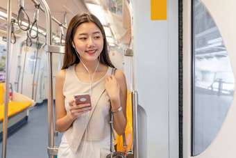 年轻的亚洲女人乘客听音乐通过聪明的移动<strong>电话地铁</strong>火车当旅行大城市日本中国人朝鲜文生活方式和每天生活通勤和运输概念