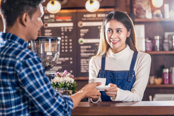 亚洲咖啡师小业务老板服务杯咖啡年轻的客户的咖啡计数器咖啡商店小业务老板和启动咖啡商店和餐厅概念