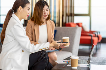 两个亚洲女商人工作与的<strong>合作伙伴</strong>业务点笔的技术移动PC现代办公室共同办公空间咖啡打破<strong>合作伙伴</strong>和的同事讨论和头脑风暴概念