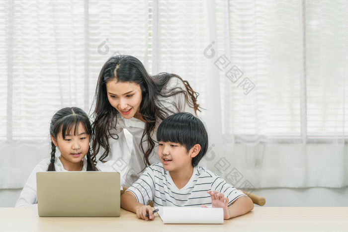 年轻的亚洲单妈妈。教学帮助女儿和儿子做首页工作与技术移动PC首页首页学校教育的关系和家庭沟通和谈话概念
