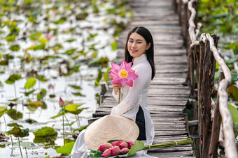 肖像美丽的<strong>越南</strong>女人与传统的<strong>越南</strong>他持有的粉<strong>红</strong>色的莲花坐着的木桥大莲花湖<strong>越南</strong>爱山东南亚洲旅行概念