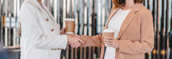 横幅网络页面封面模板两个亚洲女商人持有咖啡纸杯和手摇晃当成功合作伙伴业务协议在一起小业务与交易完成概念