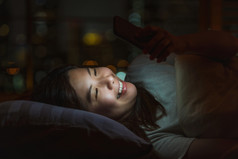 特写镜头亚洲女人睡觉和使用聪明的移动电话为社会网络视频会议调用和脸时间她的情人床上在模糊城市晚上时间生活方式和放松概念