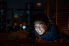 特写镜头亚洲男人。睡觉和使用聪明的移动电话为社会网络视频会议调用和脸时间她的情人床上在模糊城市晚上时间生活方式和放松工作从首页