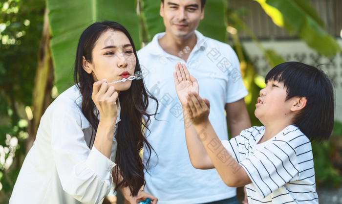 亚洲家庭包括父亲妈妈。和儿子玩的泡沫吹幸福感觉在一起公园户外和房子花园温暖的家庭首页学校假期和假期在一起