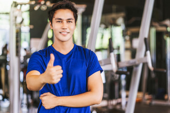 肖像年轻的亚洲男人。穿运动服装和提高手就像健身房健身体育运动复杂的的姿势位置体育运动俱乐部社区体育和医疗保健概念