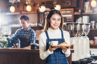 亚洲咖啡商店老板服务面包店蛋糕和咖啡杯客户咖啡商店小业务老板和启动咖啡商店和restauran女服务员和咖啡师概念