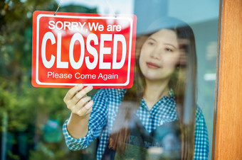 特写镜头手亚洲年轻的女人设置关闭标志的商店眼镜为欢迎的客户的咖啡商店小业务老板和启动安装开放和关闭标签概念