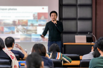 亚洲演讲者讲座与休闲西装的阶段展示通过投影仪屏幕的会议大厅<strong>研讨会</strong>会议房间观众业务<strong>教育</strong>和<strong>研讨会</strong>概念