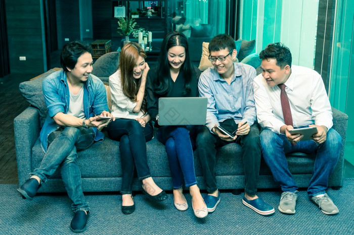 集团亚洲业务人与休闲西装使用的技术移动平板电脑移动PC和电脑为工作社会网络现代办公室人业务集团概念
