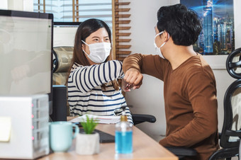 夫妇亚洲的同事们穿的外科手术面具和肘部撞与伙伴关系在一起之前工作首页办公室当新冠病毒流感大流行冠状病毒爆发新正常的概念