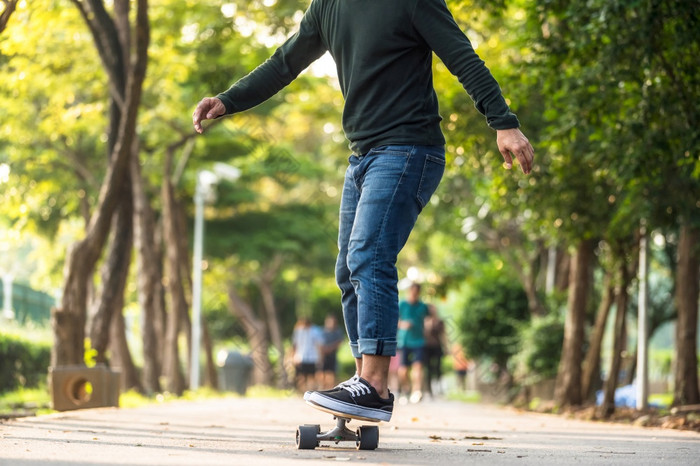 特写镜头亚洲男人。玩surfskate滑冰董事会户外公园当日出时间在照片模糊未被认可的人运行extream体育运动健康的和锻炼时尚科维德概念