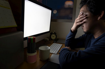 肖像亚洲商人坐着和工作硬的表格与前面电脑桌面工作的地方晚些时候与严重的行动工作硬和太晚些时候概念