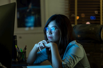 肖像亚洲女商人工作硬和看的数字图形的表格与前面电脑桌面工作场所晚些时候与严重的行动工作硬和太晚些时候概念