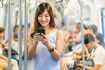 年轻的亚洲女人乘客使用社会网络通过聪明的移动<strong>电话地铁</strong>火车当旅行大城市日本中国人朝鲜文生活方式和每天生活通勤和运输概念