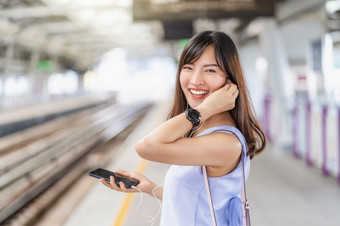 年轻的亚洲女人乘客听音乐通过聪明的移动电话地铁火车当旅行大城市日本中国人朝鲜文生活方式和每天生活通勤和运输概念